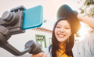 Aziatisch vrouw maken video met smartphone gimbal buitenshuis - gelukkig Aziatisch meisje hebben pret met nieuw technologie trends voor sociaal media - millennials mensen, generatie z, tech en jeugd levensstijl concept foto