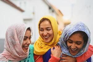 gelukkig moslim Dames wandelen in de stad centrum - Arabisch jong meisjes hebben pret uitgeven tijd en lachend samen buitenshuis - concept van levensstijl mensen cultuur en religie foto