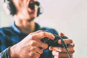 jong Mens hebben pret spelen video spellen online gebruik makend van hoofdtelefoons en microfoon - dichtbij omhoog mannetje handen gamer Holding een bedieningshendel - wijnoogst filter - mensen, technologie, het gokken concept foto