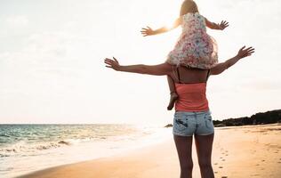 gelukkig liefhebbend familie moeder en dochter hebben pret Aan de strand Bij zonsondergang - mamma meeliften met haar kind De volgende zee gedurende zomer vakantie - ouder vakantie tijd levensstijl concept foto