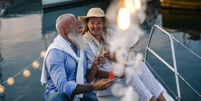 senior paar roosteren Champagne en aan het eten fruit Aan zeilboot vakantie - gelukkig ouderen mensen hebben pret vieren bruiloft verjaardag Aan boot reis - liefde verhouding en reizen levensstijl concept foto