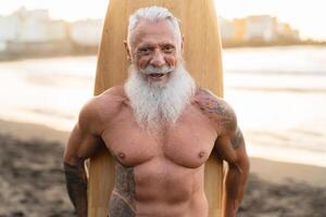 fit senior Mens hebben pret surfing Aan tropisch strand - ouderen gezond mensen levensstijl en extreem sport concept foto