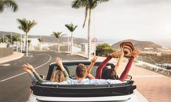 gelukkig vrienden hebben pret in converteerbaar auto Aan vakantie - jong millennial mensen het rijden Aan cabriolet in zomer vakantie - vervoer en jeugd levensstijl concept foto