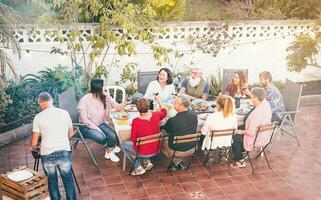 gelukkig familie aan het eten en drinken rood wijn Bij avondeten barbecue buitenshuis -mensen met verschillend leeftijden hebben pret dining samen Bij bbq partij - voedsel, ouders en weekend activiteiten foto