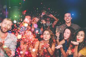 gelukkig vrienden aan het doen partij het werpen confetti in nachtclub - groep jong mensen hebben pret vieren nieuw jaar vakantie samen in disco club - jeugd cultuur vermaak levensstijl concept foto