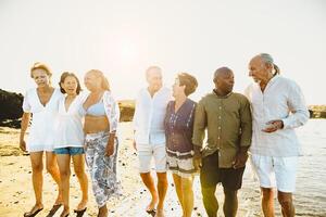 gelukkig multiraciaal senior vrienden hebben pret wandelen Aan de strand gedurende zomer vakantie - verschillend ouderen mensen genieten van vakanties foto