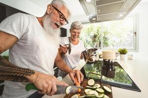 gelukkig senior paar hebben pret Koken samen Bij huis - ouderen mensen voorbereidingen treffen Gezondheid lunch in modern keuken - gepensioneerd levensstijl familie tijd en voedsel voeding concept foto