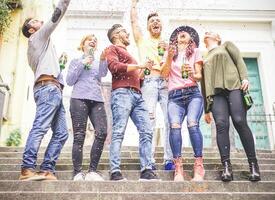 groep van gelukkig vrienden vieren samen het werpen omhoog confetti en drinken bieren - jong mensen hebben een partij Aan trap van een stedelijk Oppervlakte in de stad buitenshuis - vriendschap, plezier, levensstijl concept foto