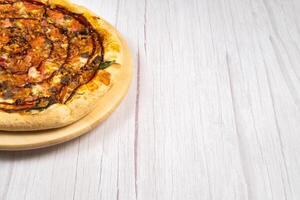 heerlijk groot pizza met spek en spinazie Aan een licht houten achtergrond foto