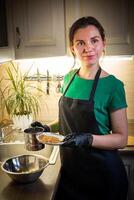 vrouw Koken smakelijk gesmolten chocola Aan tafel in keuken. foto