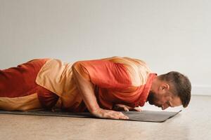 een Mens in een oranje pak doet yoga in een geschiktheid kamer. de concept van Gezondheid foto