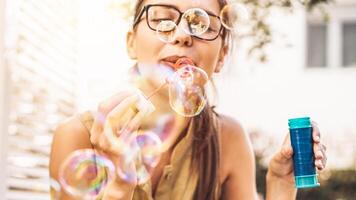 gelukkig meisje blazen zeep bubbels buitenshuis - jong vrouw hebben pret buiten - concept van plezier, mensen en vermaak foto