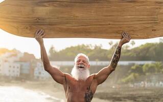 fit senior Mens hebben pret surfing Aan tropisch strand - ouderen gezond mensen levensstijl en extreem sport concept foto