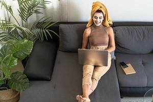 jong vrouw gebruik makend van laptop terwijl hebben huid zorg dag Bij huis foto