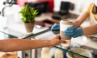 bar eigenaar werken enkel en alleen met nemen weg bestellingen gedurende corona virus het uitbreken - jong vrouw arbeider vervelend gezicht chirurgisch masker geven koffie naar klant - gezondheidszorg en drankjes concept foto