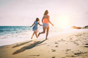 gelukkig liefhebbend familie moeder en dochter rennen en hebben pret Aan de strand Bij zonsondergang - mam spelen met haar kind De volgende naar oceaan gedurende vakantie - ouder, vakantie, familie levensstijl concept foto