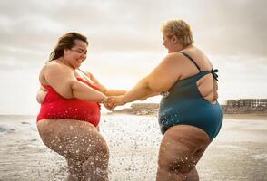 gelukkig plus grootte Dames hebben pret Aan de strand gedurende zomer vakantie - golvend zelfverzekerd mensen levensstijl concept foto