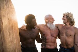 gelukkig fit surfers met verschillend leeftijd en ras hebben pret surfing samen Bij zonsondergang tijd - extreem sport levensstijl en vriendschap concept foto