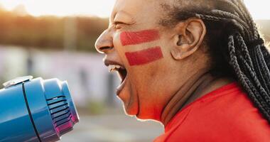 Afrikaanse Amerikaans voetbal ventilator met geschilderd gezicht en megafoon juichen voor haar team - sport vermaak concept foto