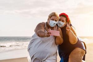 gelukkig plus grootte Dames nemen selfie met mobiel smartphone Aan de strand - te zwaar vrienden hebben pret Aan vakantie gedurende corona virus pandemisch - gezondheidszorg en technologie concept foto