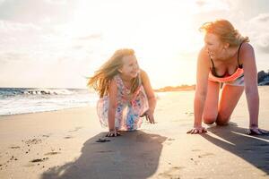 gelukkig moeder en dochter hebben pret Aan de strand in vakantie - mam spelen met haar kind gedurende hun vakantie - familie levensstijl en liefde concept foto