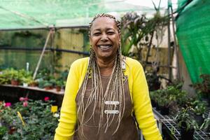 gelukkig Afrikaanse vrouw glimlachen voorkant van camera terwijl werken in bloem tuin winkel foto
