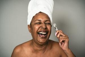 gelukkig afro senior vrouw gebruik makend van jade rol gedurende huid zorg spa dag - mensen welzijn levensstijl concept foto