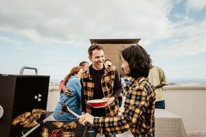 gelukkig multigenerationeel mensen hebben pret aan het doen barbecue rooster Bij huis op het dak - zomer bijeenkomsten en voedsel concept foto