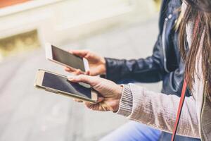 dichtbij omhoog van jong Dames handen gebruik makend van mobiel slim telefoons zittend in de stad buitenshuis - nieuw mensen verslaving naar elektronisch apparaten - concept van technologie, sociaal netwerk, media, vermaak foto