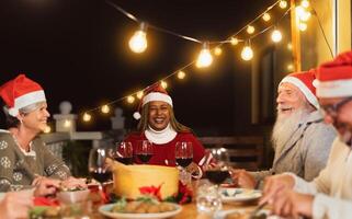 gelukkig senior vrienden dining samen gedurende Kerstmis vakantie viering Aan huis patio partij foto