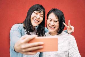 Aziatisch moeder en dochter nemen foto selfie met mobiel smartphone buitenshuis - gelukkig Chinese familie hebben pret met nieuw trends technologie apps - familie, tech en levensstijl mensen concept