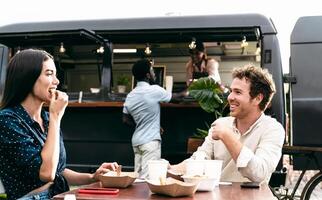 gelukkig multiraciaal vrienden hebben pret aan het eten in een straat voedsel vrachtauto markt foto