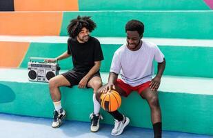 gelukkig afro Amerikaans vrienden luisteren muziek- binnen basketbal rechtbank met wijnoogst boombox stereo - stedelijk straat mensen levensstijl foto