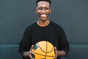 gelukkig jong Afrikaanse Mens spelen basketbal buitenshuis - stedelijk sport levensstijl concept foto