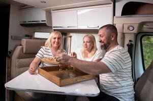 een familie van drie is spelen een bord spel terwijl zittend in een camper foto