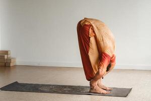 een Mens in een oranje pak doet yoga in een geschiktheid kamer. de concept van Gezondheid foto