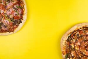 twee verschillend heerlijk groot pizza's Aan een geel achtergrond foto