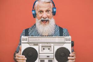 gelukkig senior Mens luisteren naar muziek- met boombox en hoofdtelefoons buitenshuis - gek hipster mannetje hebben pret met wijnoogst stereo - concept van ouderen mensen levensstijl foto