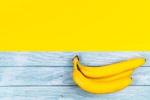 geel bananen liggen Aan een blauw houten achtergrond en een geel achtergrond foto