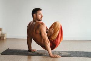 een Mens met een naakt torso doet yoga staand Aan zijn handen binnenshuis. geschiktheid trainer foto