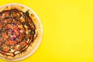 heerlijk groot pizza met spek en spinazie Aan een geel achtergrond foto