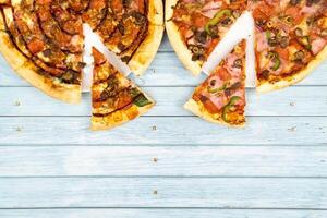 twee verschillend heerlijk groot pizza's Aan een blauw houten achtergrond foto