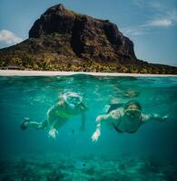 een weinig meisje en haar moeder zwemmen in maskers onder water in de buurt de strand van le Morne in de Indisch oceaan Aan de eiland van Mauritius foto