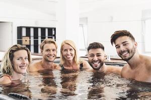 gelukkig vrienden genieten van vakanties in jacuzzi luxe huis - jong mensen hebben pret samen in heet kuip - jeugd millennial generatie en welzijn levensstijl vakantie foto