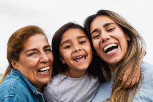 gelukkig spaans multigenerationeel familie glimlachen in de camera - kind hebben pret met haar moeder en grootmoeder buitenshuis foto