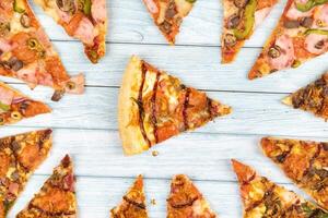 veel van heerlijk driehoekig pizza plakjes Aan een blauw houten achtergrond foto