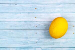 een geheel geel meloen leugens Aan een blauw houten achtergrond.zomer concept foto