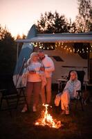 de familie is ontspannende samen door de kampvuur in de buurt hun mobiel huis. avond familie vakantie foto