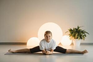 een tiener- meisje in sport- kleren doet yoga in een geschiktheid kamer foto