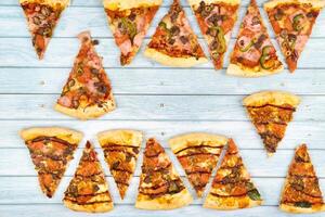 veel van heerlijk driehoekig pizza plakjes Aan een blauw houten achtergrond foto